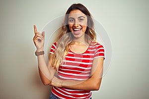 Young beautiful woman wearing red stripes t-shirt over white isolated background with a big smile on face, pointing with hand and