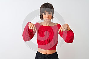 Young beautiful woman wearing red summer t-shirt standing over isolated white background Pointing down looking sad and upset,