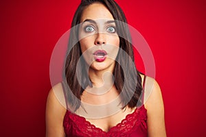 Young beautiful woman wearing sexy lingerie over red isolated background afraid and shocked with surprise expression, fear and