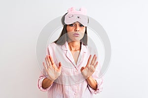 Young beautiful woman wearing sleep mask and pajama over isolated white background Moving away hands palms showing refusal and