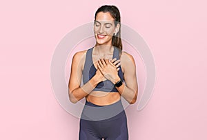 Young beautiful woman wearing sportswear smiling with hands on chest with closed eyes and grateful gesture on face