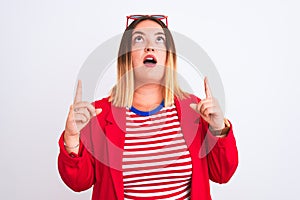 Young beautiful woman wearing striped t-shirt and jacket over isolated white background amazed and surprised looking up and