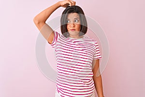 Young beautiful woman wearing striped t-shirt standing over isolated pink background confuse and wondering about question