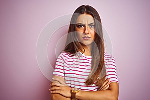 Young beautiful woman wearing striped t-shirt standing over isolated pink background skeptic and nervous, disapproving expression