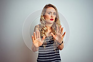 Young beautiful woman wearing stripes t-shirt standing over white isolated background Moving away hands palms showing refusal and