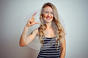 Young beautiful woman wearing stripes t-shirt standing over white isolated background smiling and confident gesturing with hand