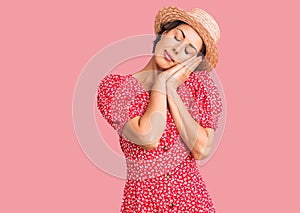 Young beautiful woman wearing summer hat sleeping tired dreaming and posing with hands together while smiling with closed eyes
