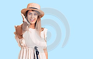 Young beautiful woman wearing summer hat and t-shirt smiling friendly offering handshake as greeting and welcoming photo