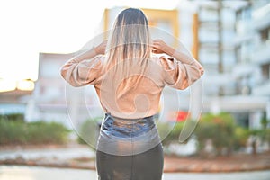 Young beautiful woman wearing sweater and skirt standing backwards at the town street