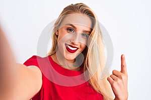 Young beautiful woman wearing t-shirt make selfie by camera over isolated white background surprised with an idea or question