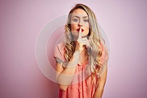 Young beautiful woman wearing t-shirt standing over pink isolated background asking to be quiet with finger on lips