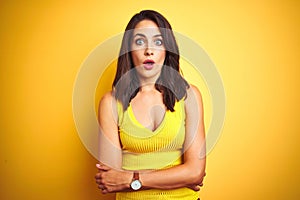 Young beautiful woman wearing t-shirt standing over yellow isolated background afraid and shocked with surprise expression, fear