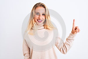 Young beautiful woman wearing turtleneck sweater standing over isolated white background showing and pointing up with finger