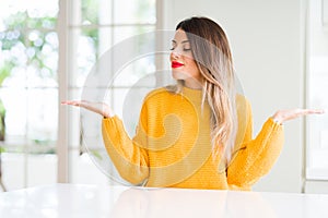 Young beautiful woman wearing winter sweater at home Smiling showing both hands open palms, presenting and advertising comparison