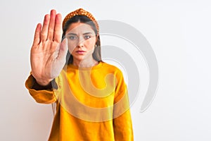 Young beautiful woman wearing yellow sweater and diadem over isolated white background doing stop sing with palm of the hand