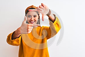 Young beautiful woman wearing yellow sweater and diadem over isolated white background smiling making frame with hands and fingers