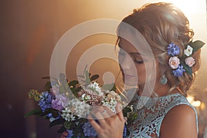 Young beautiful woman in wedding dress with bouquet of flowers. Wedding hairstyle, flowers in hair.