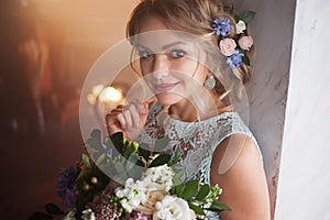 Young beautiful woman in wedding dress with bouquet of flowers. Wedding hairstyle, flowers in hair.