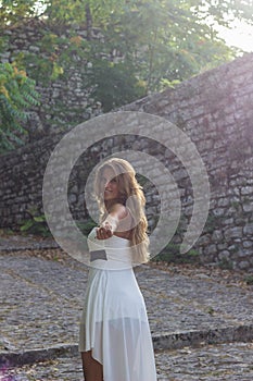 Beautiful woman wearing white dress on stone road