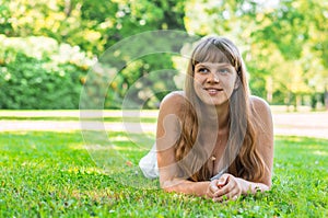 Young beautiful woman in white dress lying on the grass
