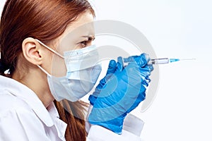 Young beautiful woman on white isolated background in medical mask holds syringe, medicine, doctor