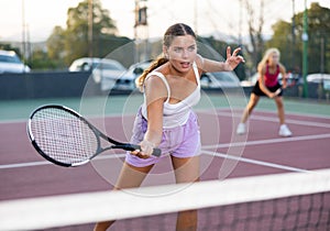 Young beautiful woman in white t-shirt playing tennis close to net
