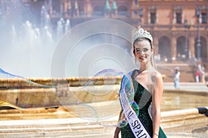 Young and beautiful woman winner of a beauty contest dressed elegant and wearing a crown of diamonds, is in sevilla in the famous