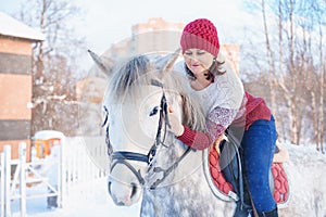 Young beautiful woman in winter with beautiful white horse