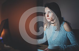 Young beautiful woman working on modern loft office at night. Girl using contemporary desktop computer, blurred