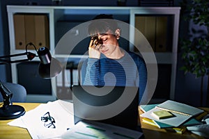 Young beautiful woman working at the office at night tired rubbing nose and eyes feeling fatigue and headache