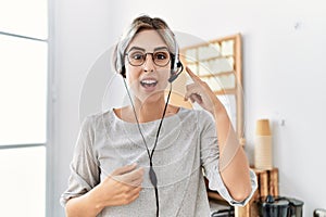 Young beautiful woman working at the office wearing operator headset smiling happy pointing with hand and finger