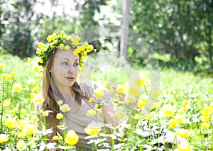 The young beautiful woman in a wreath from Globeflower in field