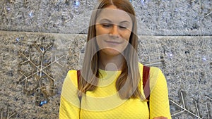 Young beautiful woman in a yellow blouse at a mall. Christmas New Year decoration.