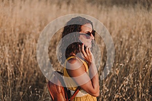 Young beautiful woman in yellow dress talking with mobile phone. Countryside. Outdoors. Travel concept. Sunset