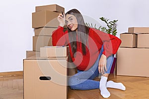 A young beautiful women makes her notes and plans in her new flat,apartment. Young woman packing cardboard box. Moving house