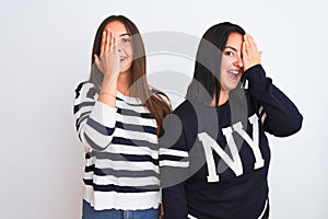 Young beautiful women wearing casual clothes standing over isolated white background covering one eye with hand, confident smile