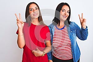 Young beautiful women wearing casual clothes standing over isolated white background smiling looking to the camera showing fingers