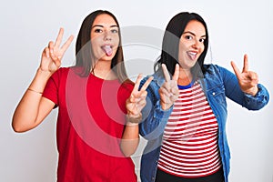 Young beautiful women wearing casual clothes standing over isolated white background smiling with tongue out showing fingers of