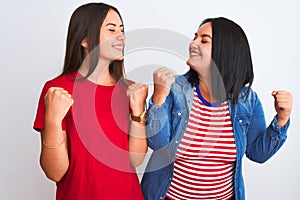 Young beautiful women wearing casual clothes standing over isolated white background very happy and excited doing winner gesture