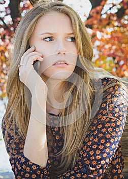 Young beautiful worried girl calling on mobile phone in park