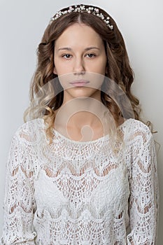 Young beautiful young girl with long curly hair, no makeup with a clean face with a wreath on his head portrait in the studio on a