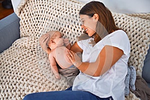 Young beautifull woman and her baby on the sofa over blanket at home