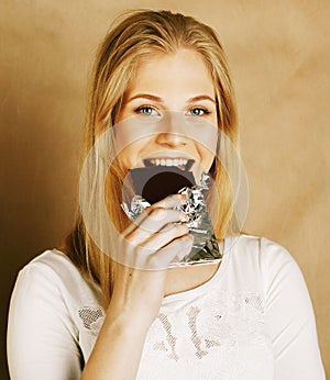 Young beauty blond teenage girl eating chocolate smiling