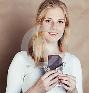 Young beauty blond teenage girl eating chocolate smiling