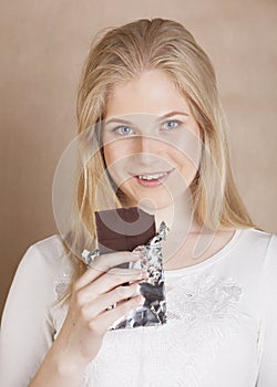 Young beauty blond teenage girl eating chocolate smiling