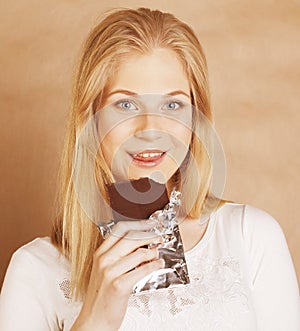 young beauty blond teenage girl eating chocolate smiling