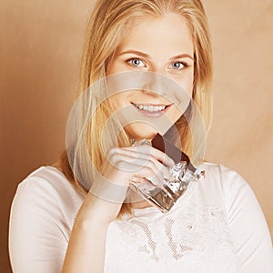 Young beauty blond teenage girl eating chocolate smiling