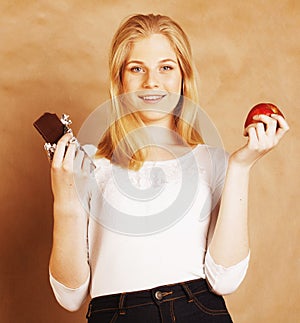 Young beauty blond teenage girl eating chocolate smiling, choice