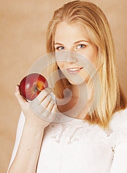 Young beauty blond teenage girl eating chocolate smiling, choice between sweet and apple