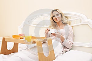 young beauty blond woman having breakfast in bed early sunny morning, princess house interior room, healthy lifestyle